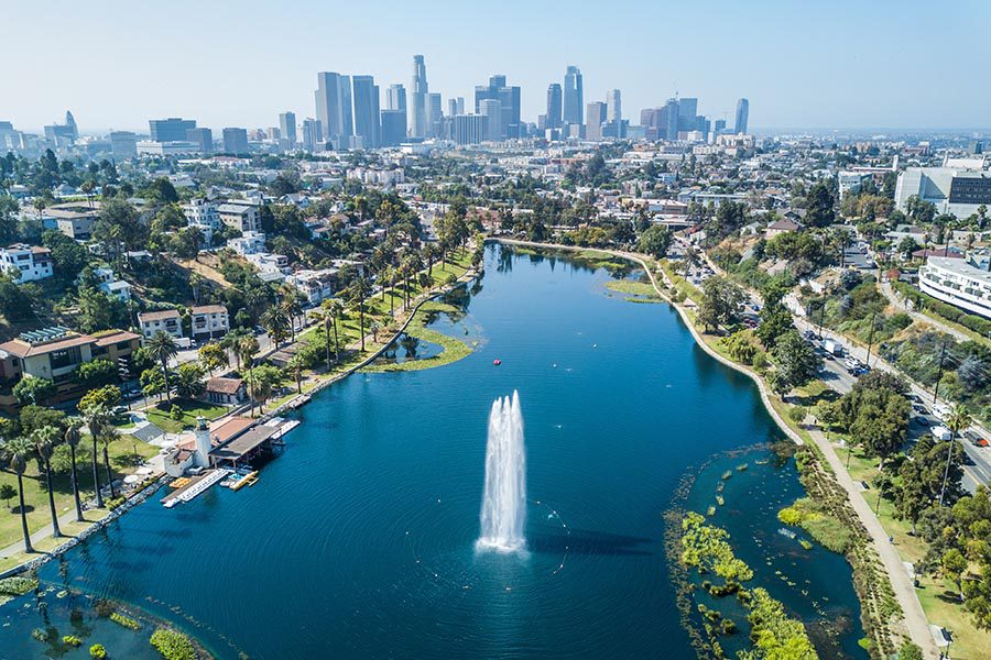 About Our Agency - Echo Park in California, Lake With Fountain in the Foreground, the Los Angeles Skyline in the Distance