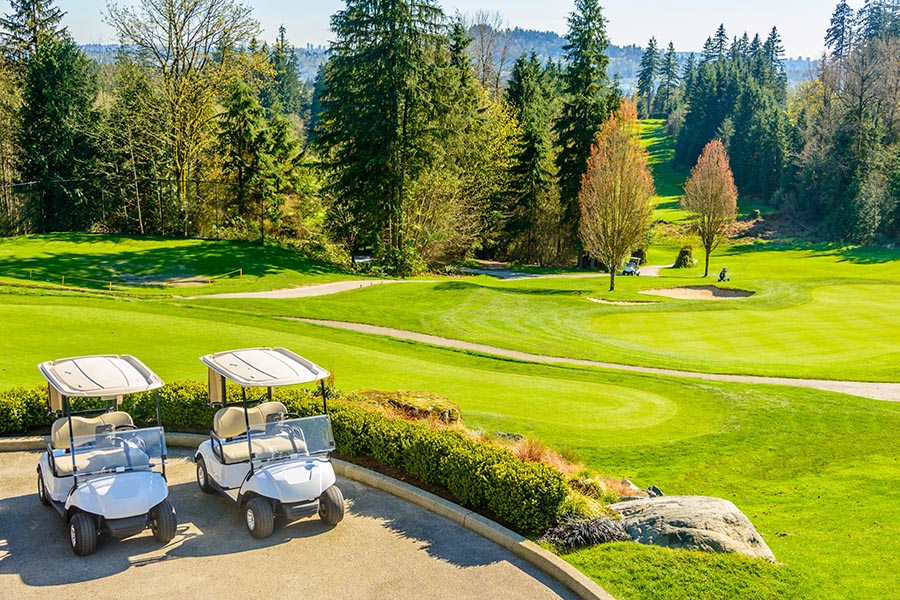 Specialized Business Insurance - Beautiful Golf Course With Golf Carts in the Foreground, Mountains and Pine Trees in the Background